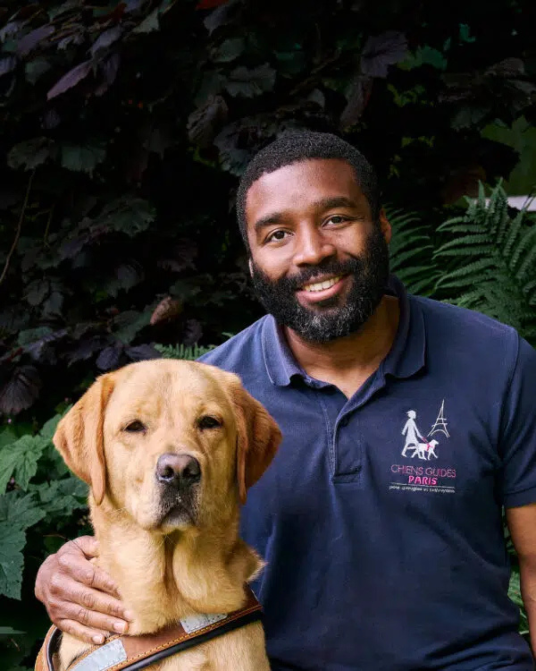 Photo de Dimitri, instructeur en locomotion à l’École de Chiens Guides, photographié avec Taoki, un labrador de couleur sable situé à sa gauche.
