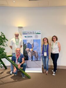 Photo de groupe devant le panneau de l'IGDF. Cécile, Benjamin, Frédérique et une famille d'accueil sont présents sur la photo.
