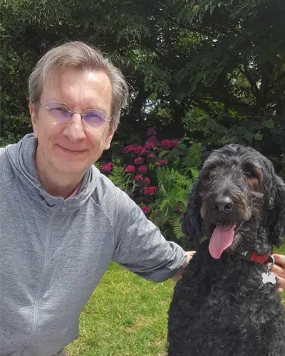 Jean-François Brunet posant avec Leroy, chien guide de race labradoodle. 