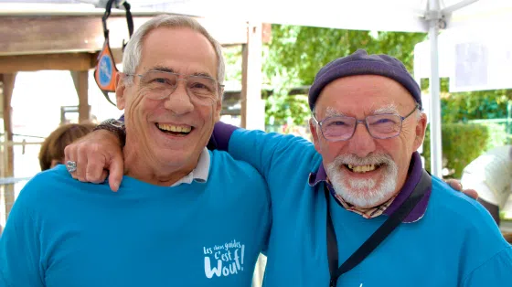Bernard et un bénévole se tiennent bras dessus bras dessous, le sourire aux lèvres.
