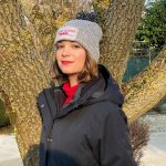 Bonnet gris clair avec pompon gris foncé , brodé avec la phrase " Chiens guides Paris " sur le devant du bonnet