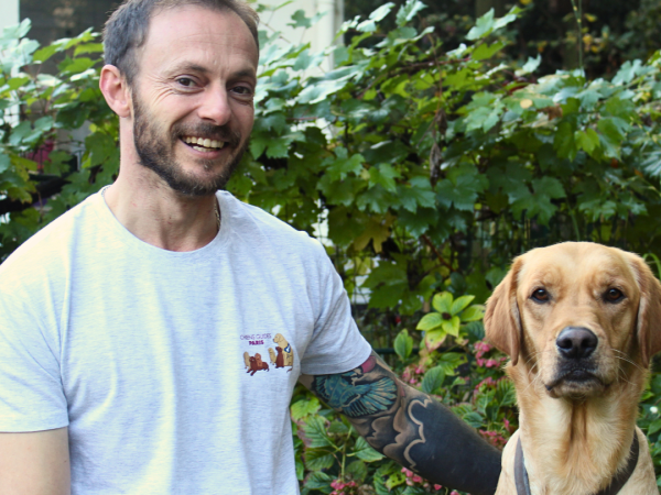 Mathieu qui porte le t-shirt Chiens Guides Paris posant avec un chien