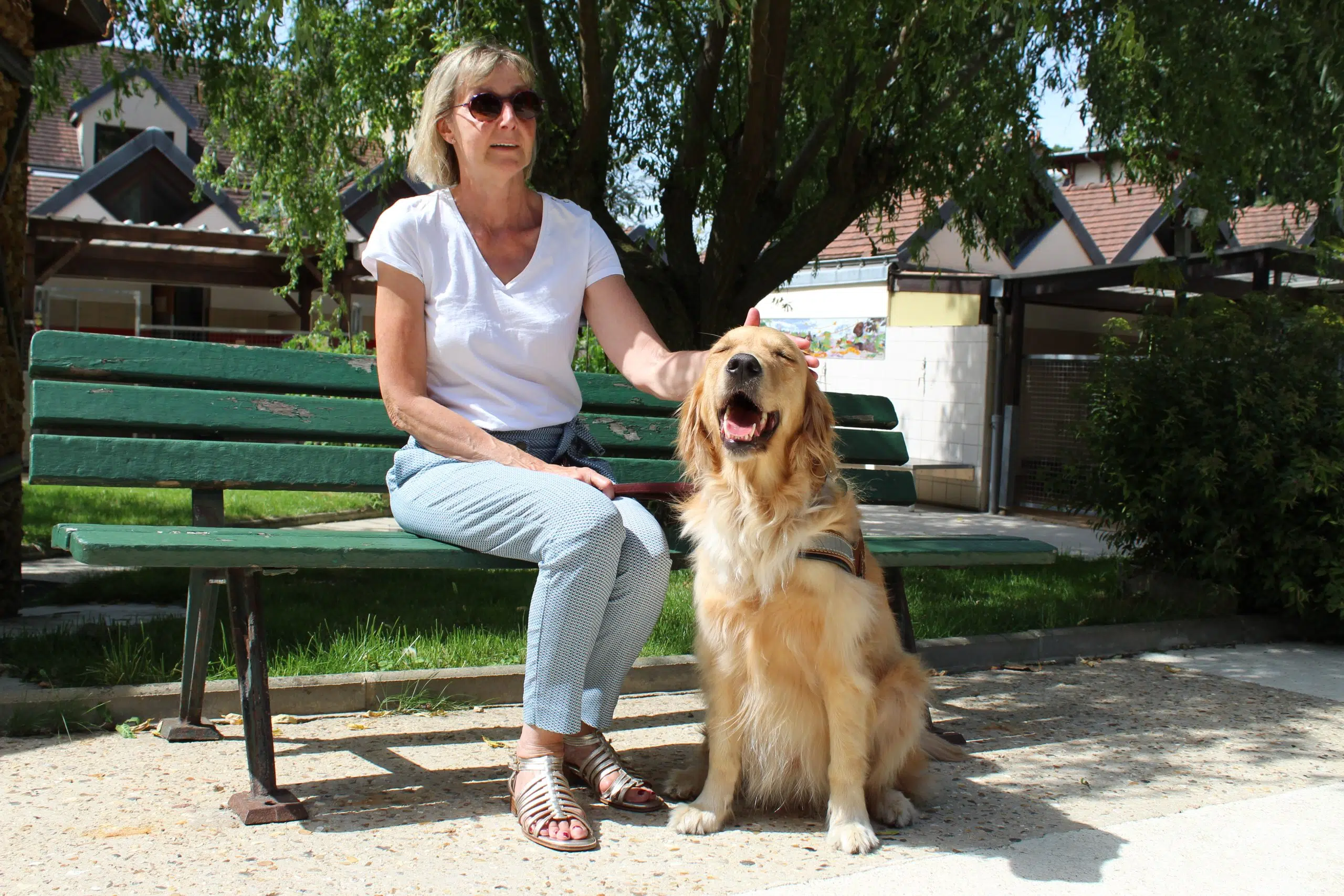 Claudite, maitre chien guide, avec Ruben, golden retriever sable, assise sur un des bancs de l'Ecole