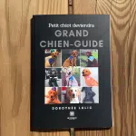 Livre de poche "Petit chiot deviendra grand chien guide". La couverture est noire, avec au centre plusieurs petits carrés contenant des photos de chiens guides.
