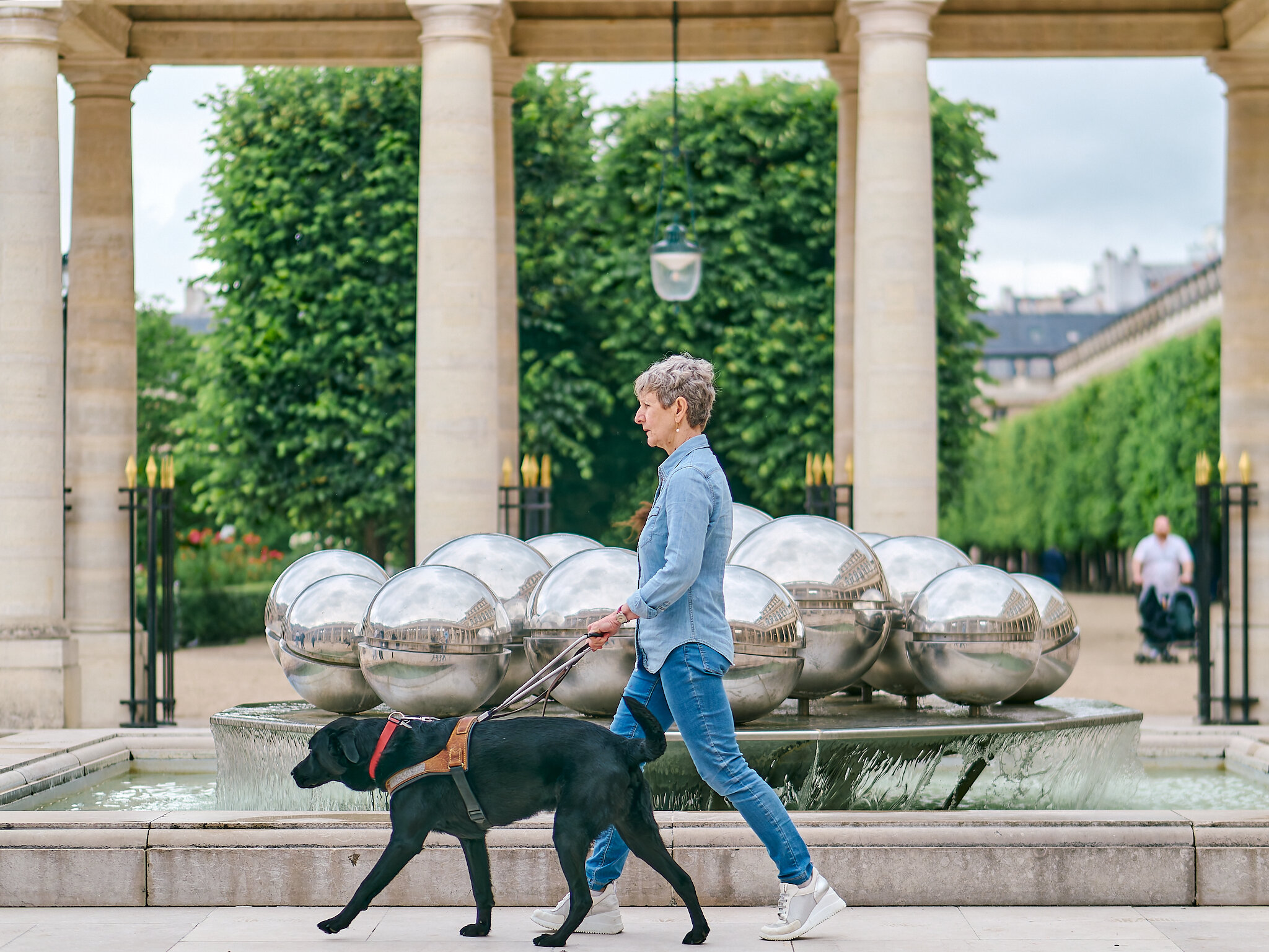 Photo de Martine , une bénéficiaire qui marche dans la rue avec son chien Rusty, un labrador noir 