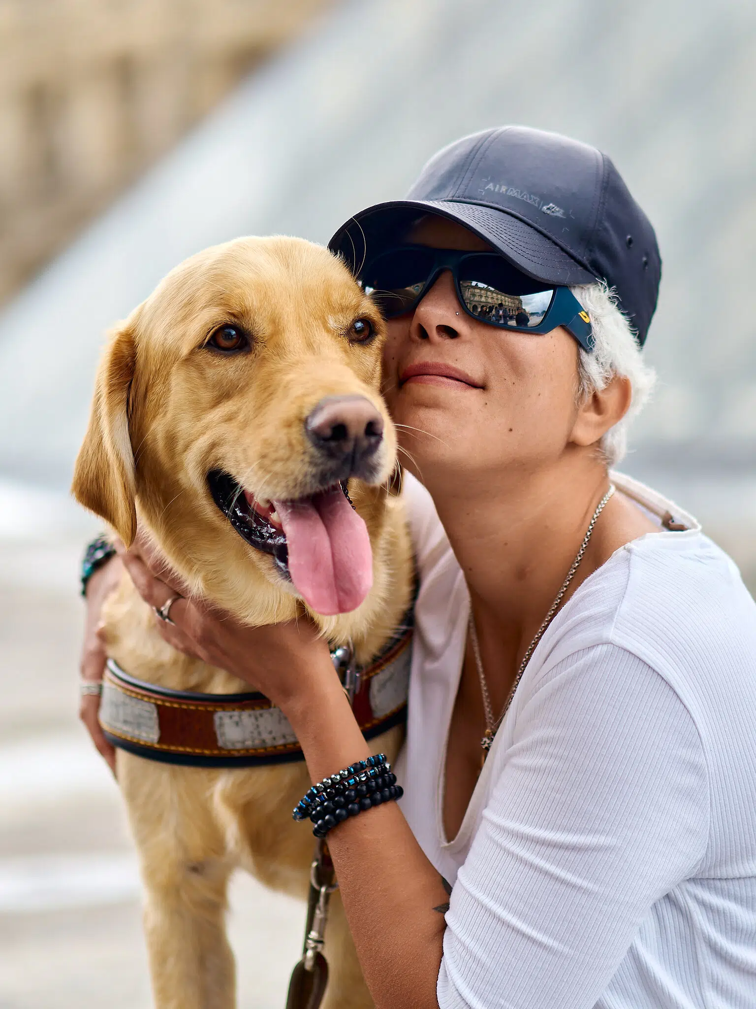 Photo de Valentine et son chien guide Timy devant la pyramide du Louvre