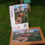 Photo du puzzle de l’École de Chiens Guides avec la boîte installée à côté. Le puzzle représente Up, un labrador de couleur sable portant son harnais.