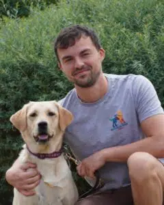 Tom posant aux côtés d'un chien guide